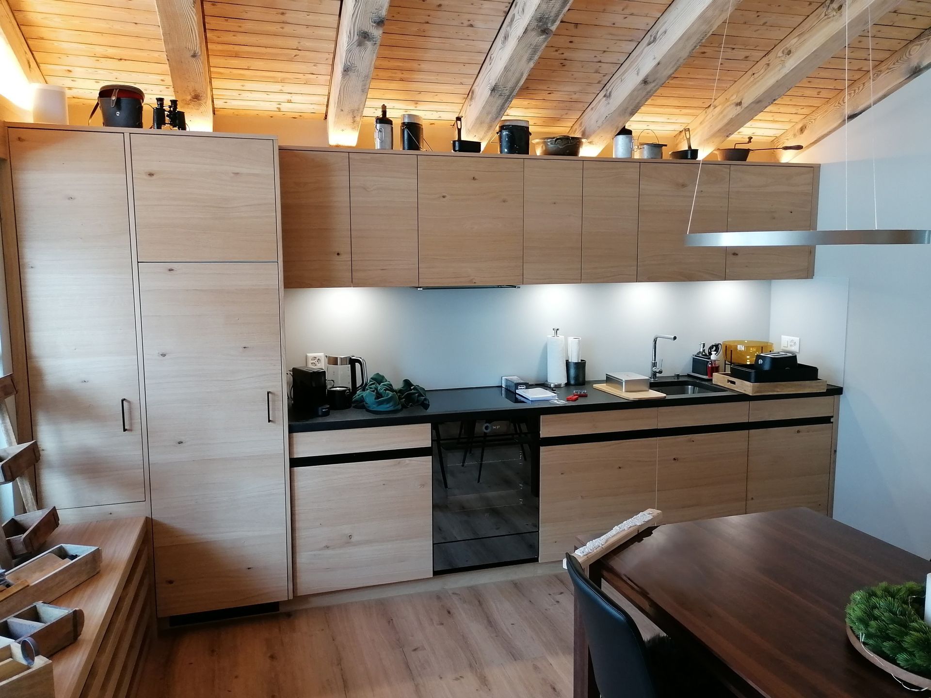 Eine Küche mit Holzschränken, Spüle und Herd. Foto von der Holzprofi Zermatt AG