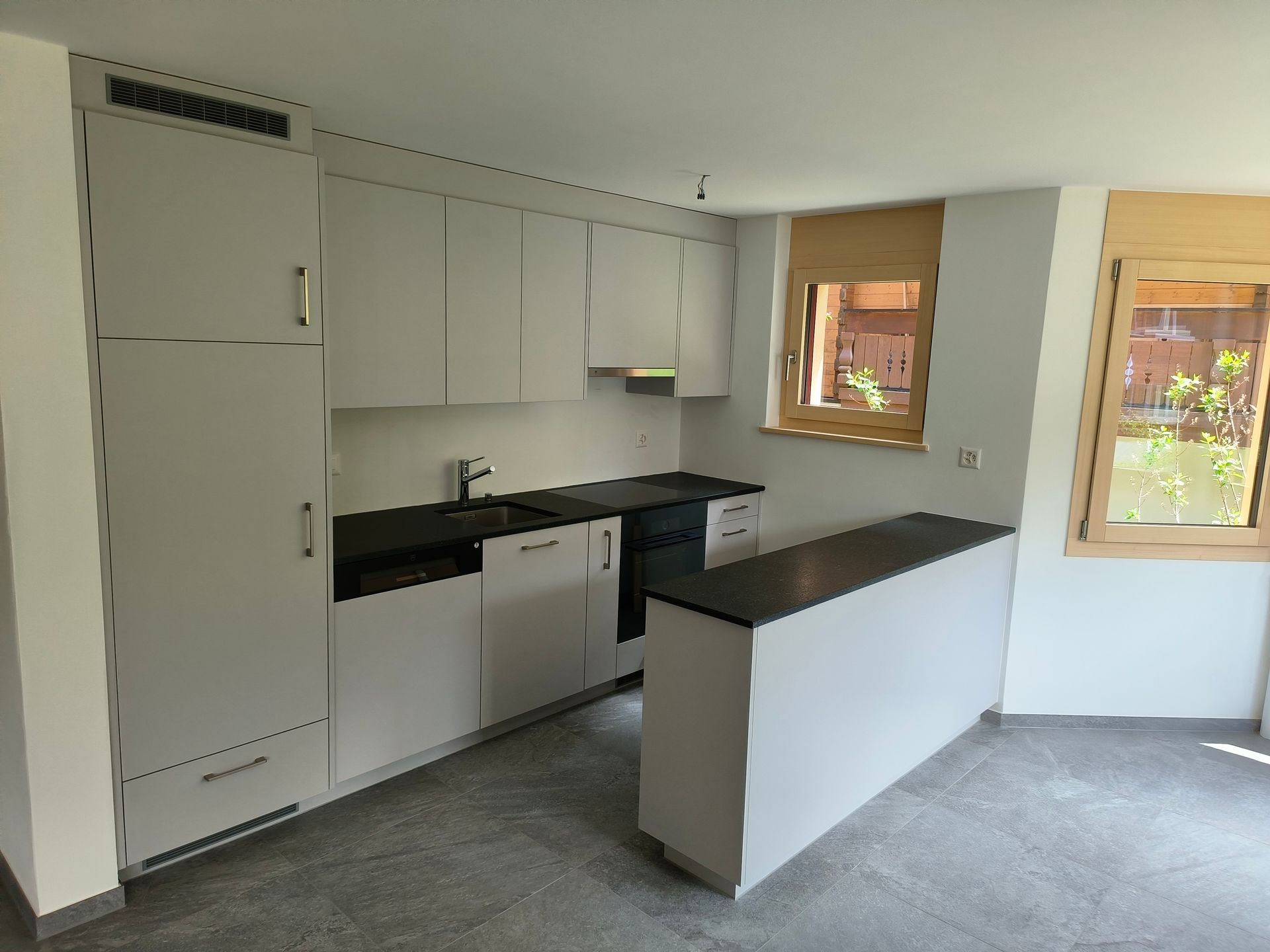 Eine Küche mit weissen Schränken. Foto von der Holzprofi Zermatt AG