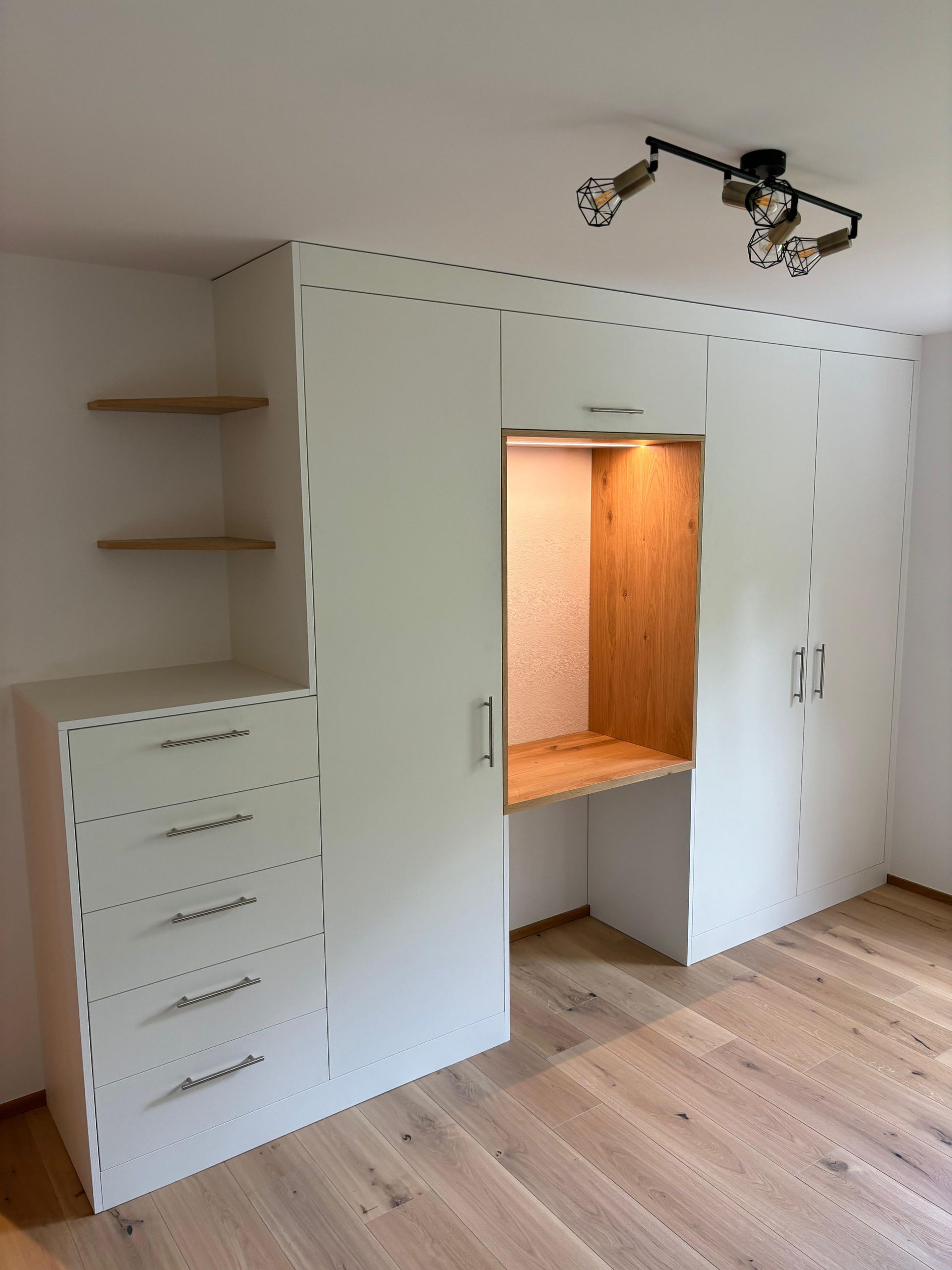 Ein Holztisch mit Schubladen steht in einem Raum. Foto von der Holzprofi Zermatt AG