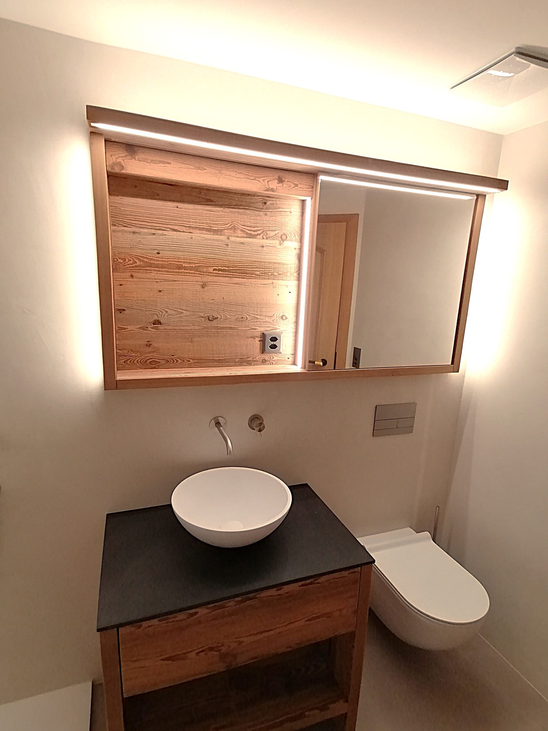 Ein Badezimmer mit einem Holzwaschtisch und einem Waschbecken. Foto von der Holzprofi Zermatt AG