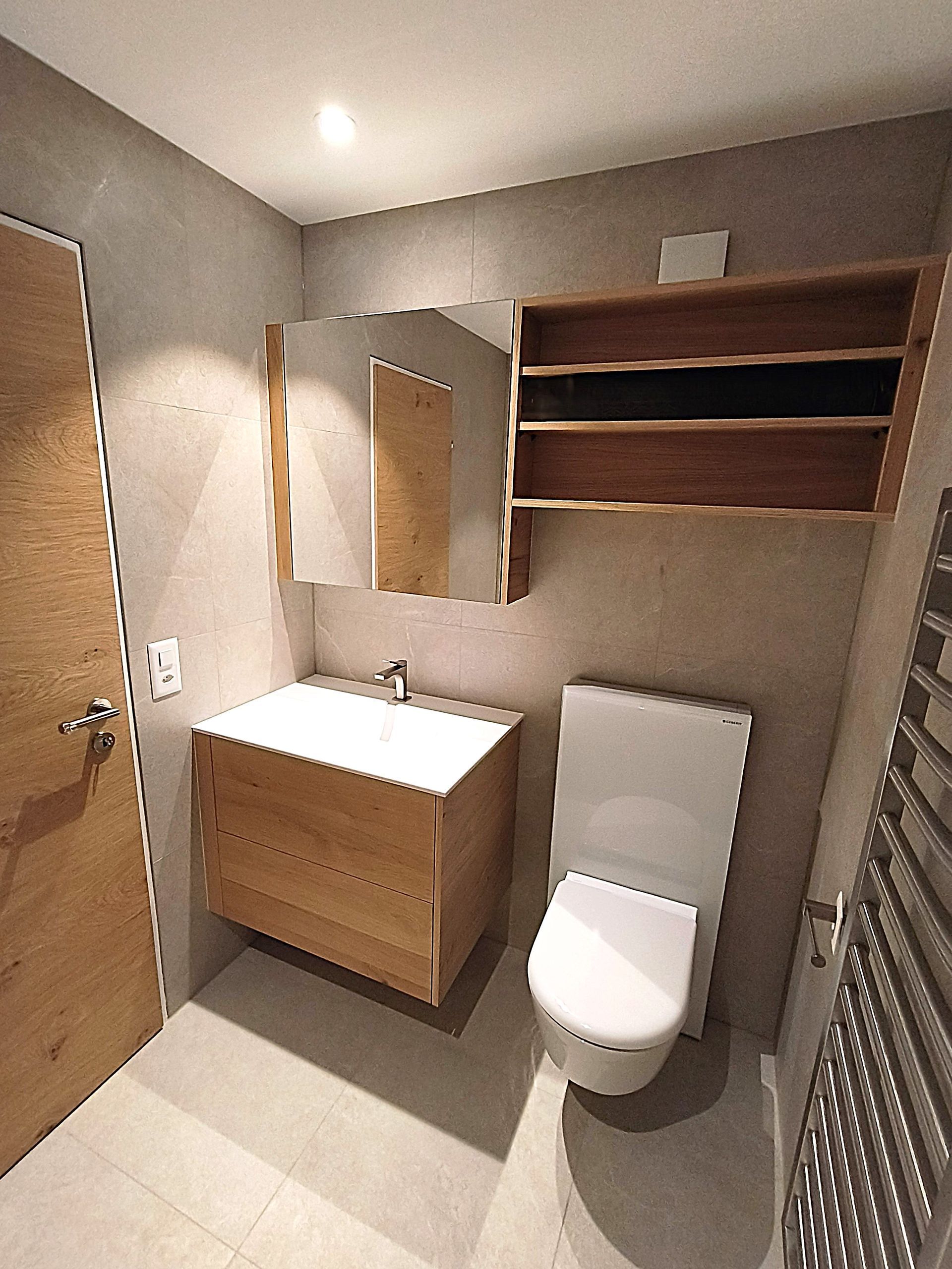 Ein Badezimmer mit Waschbecken, Spiegel und Holzschrank. Foto von der Holzprofi Zermatt AG