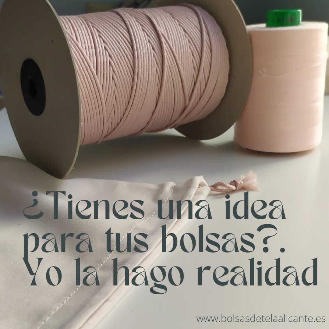 Un carrete de hilo rosa reposa sobre una mesa al lado de una botella de hilo.