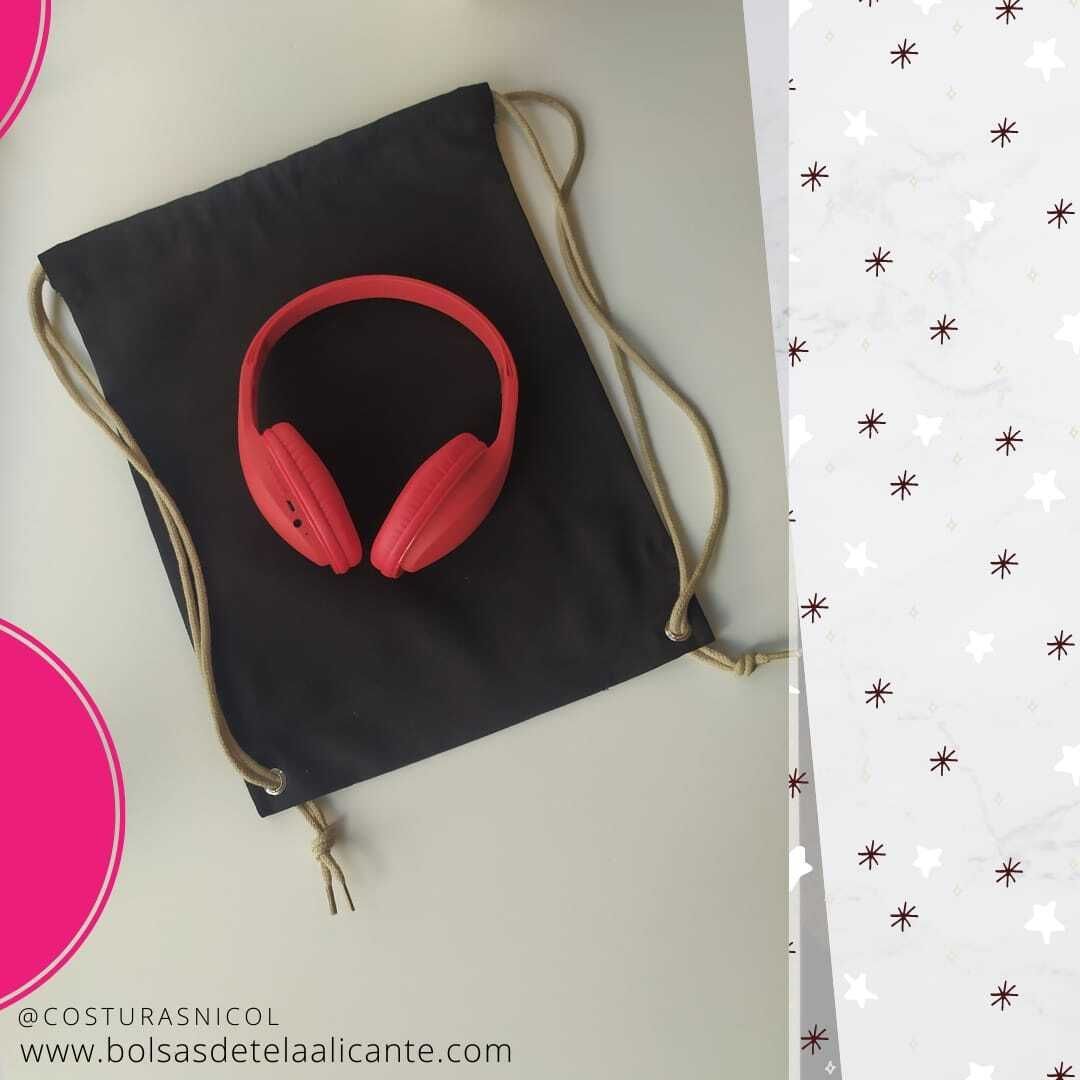 Un par de auriculares rojos sobre una bolsa negra con cordón.