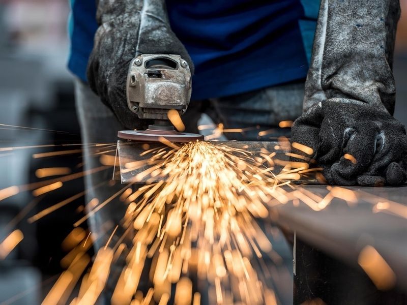 Ein Mann schleift ein Stück Metall, aus dem Funken fliegen.