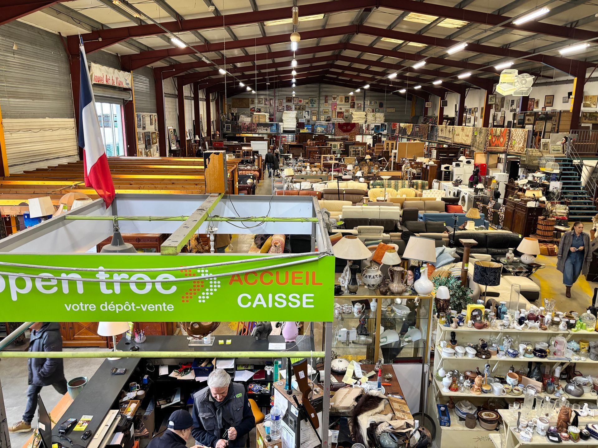 Grand entrepôt de meubles et d'objets ; des clients font leurs achats dans un magasin Open troc.