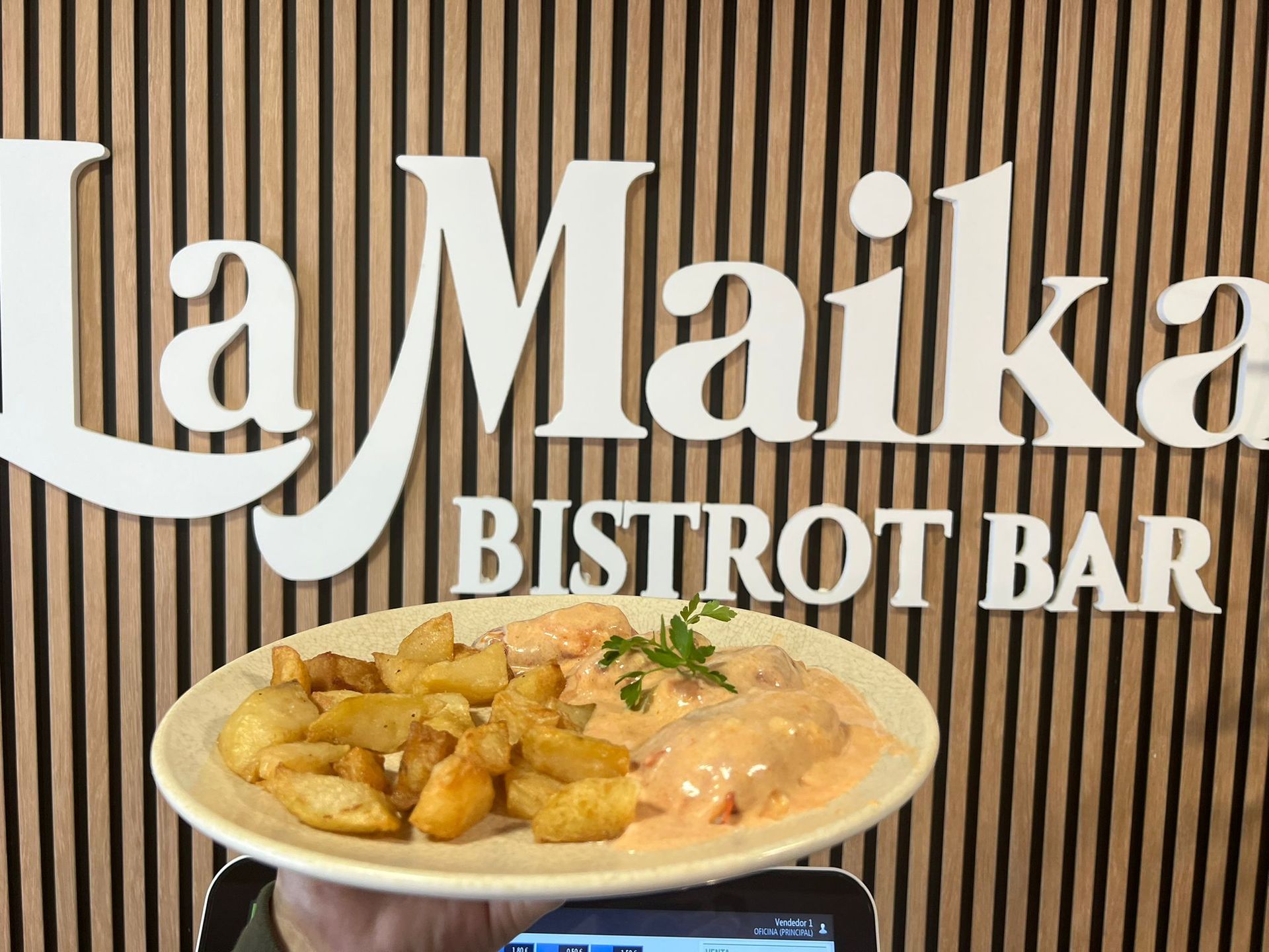 Plato de comida con patatas y salsa delante de un cartel de 