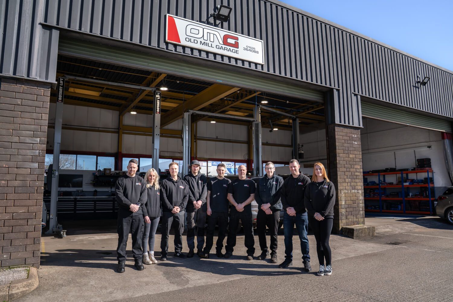 A group of people are posing for a picture in front of a garage.
