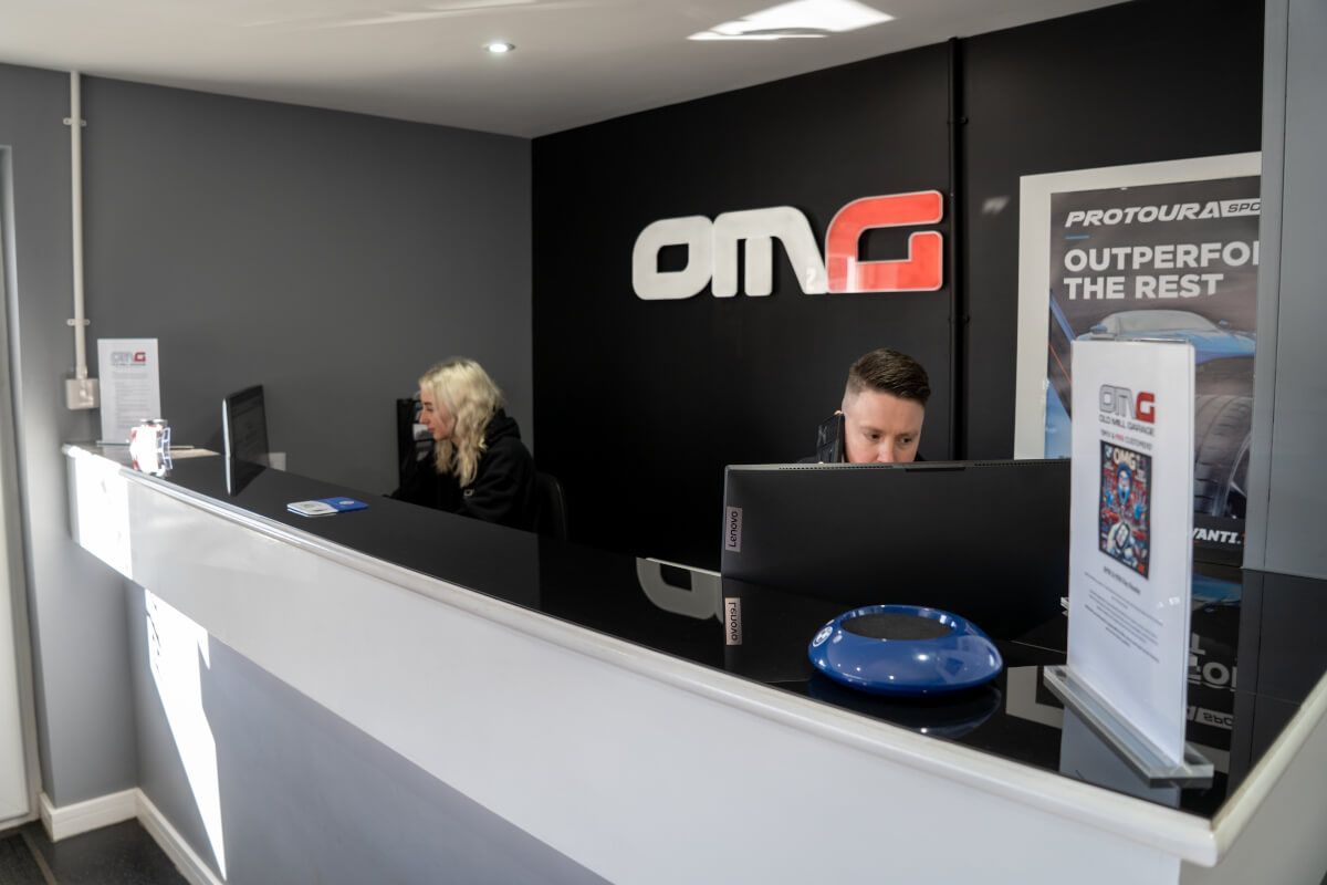 A man and a woman are sitting at a counter in a car dealership.