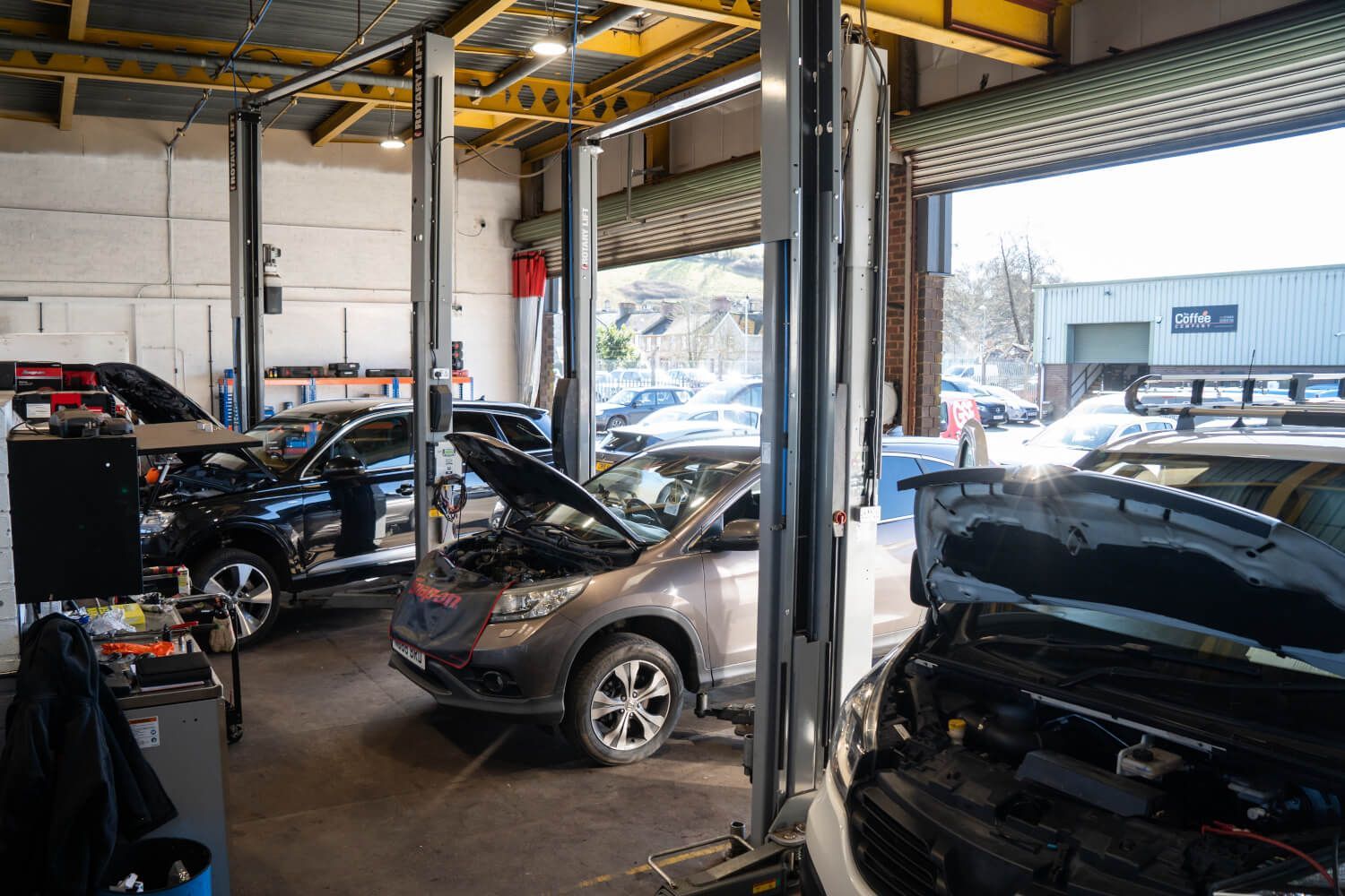 A row of cars are sitting on lifts in a garage.