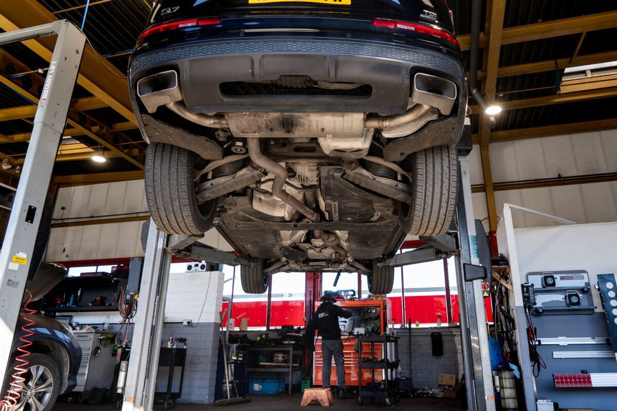 A car is sitting on a lift in a garage.