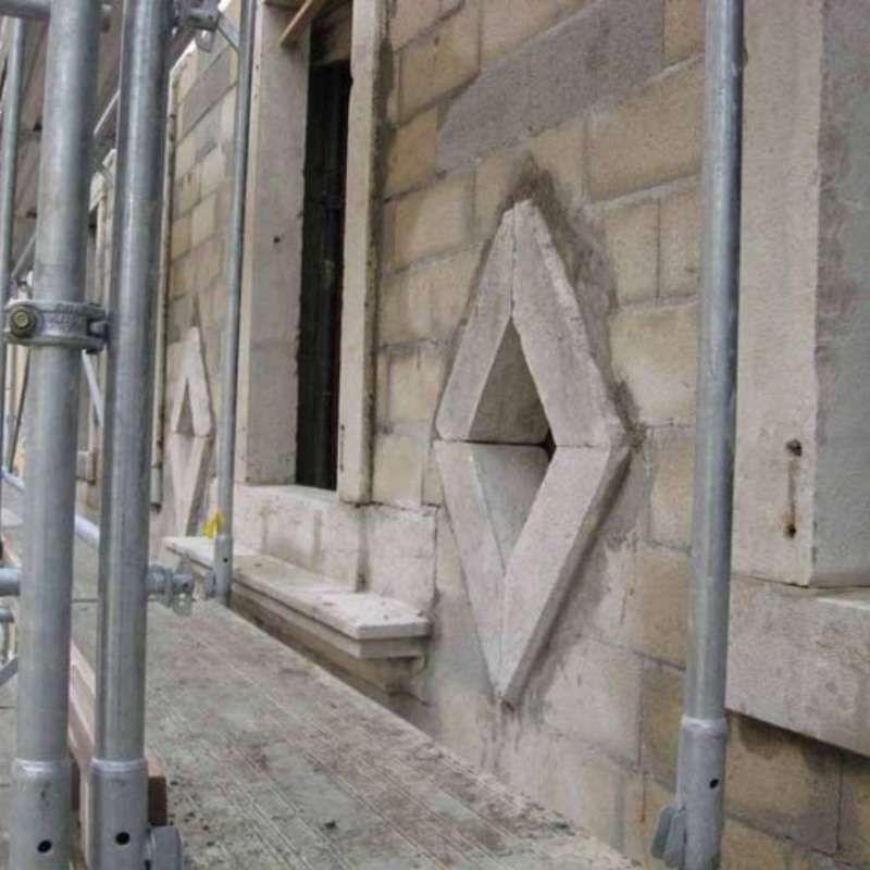 Un bâtiment en brique avec un échafaudage autour et une fenêtre en forme de losange