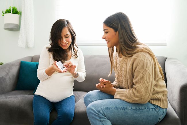 Zwei Frauen sitzen auf einem Sofa und unterhalten sich.