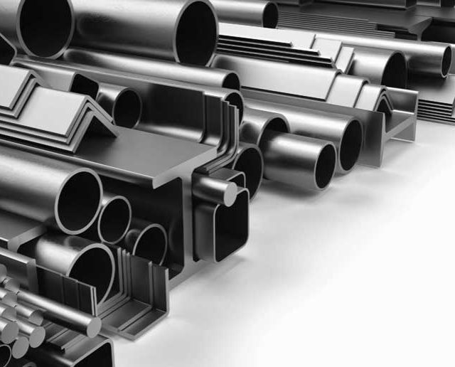Verschiedene graue Metallrohre und Armaturen, gestapelt in einem Lager oder Industriegebäude