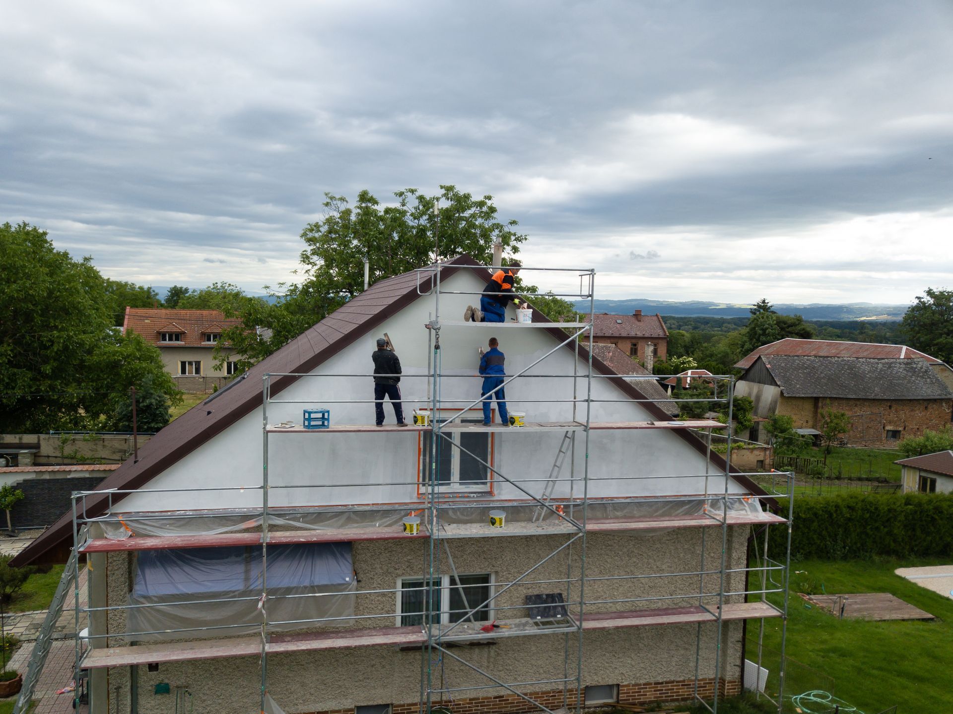 Trois hommes isolent une maison par une façade sur un échafaudage