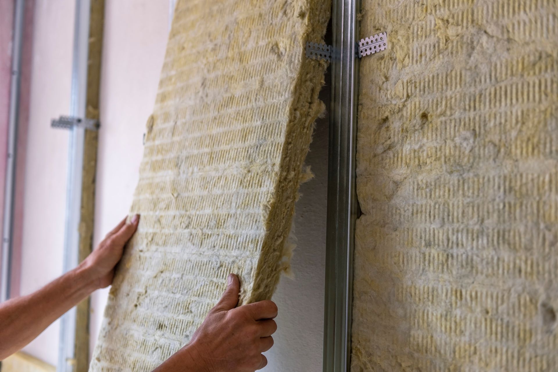 Ouvrier isolant le mur d'une pièce avec une isolation thermique en laine de roche minérale