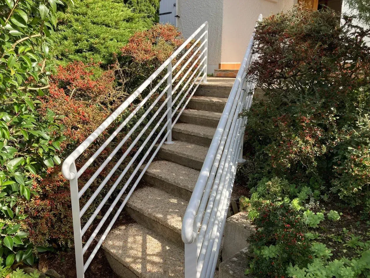Rambarde en métal peinte en blanc sur escalier en pierre
