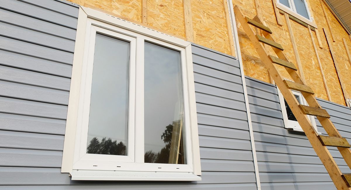 Pose d'un bardage en bois gris sur une façade en bois composite
