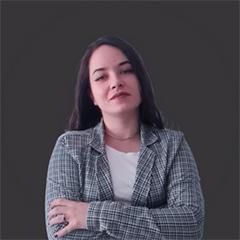 Uma mulher com uma jaqueta xadrez está de pé com os braços cruzados.