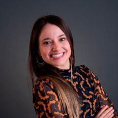 Uma mulher com uma blusa estampada de oncinha está sorrindo com os braços cruzados.