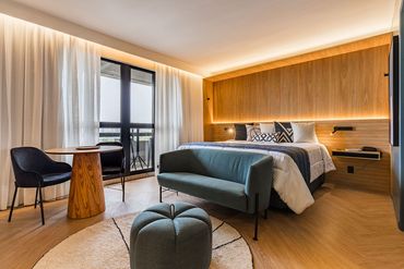 Um quarto de hotel com uma cama, sofá, mesa e cadeiras.