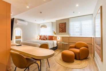 Um quarto de hotel com duas camas, uma cadeira, uma mesa e um espelho.
