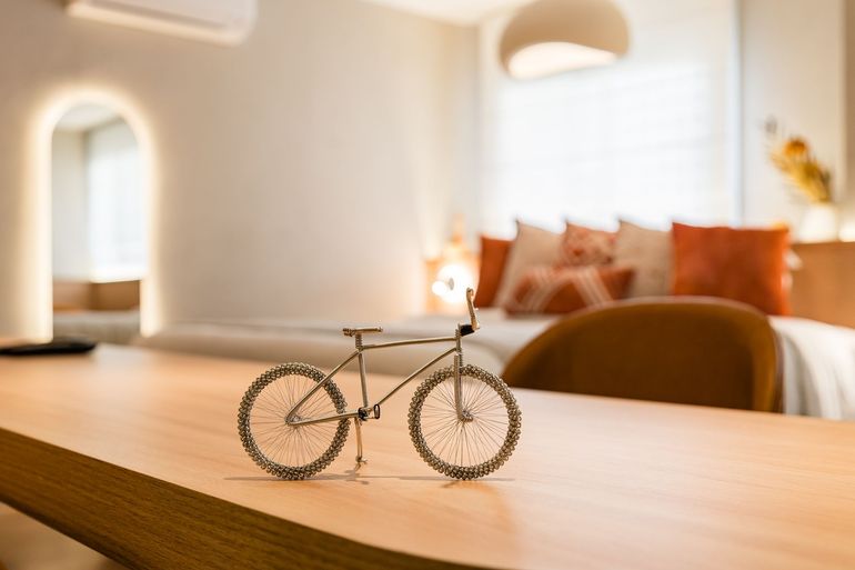 Uma pequena bicicleta está sobre uma mesa de madeira em um quarto.