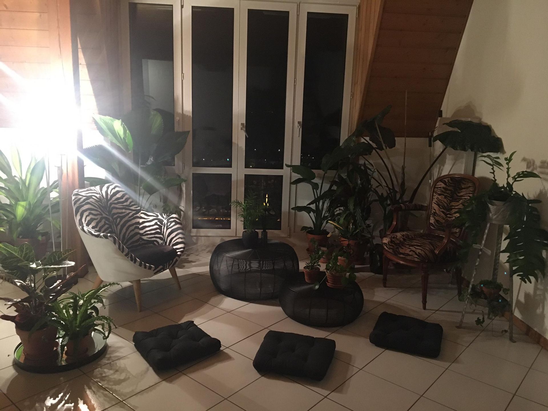 Pièce sombre aux murs couleur crème, fenêtre avec store blanc, radiateur en dessous et lampe dans un coin.