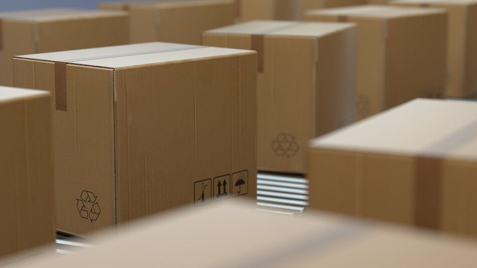 Una fila de cajas de cartón están apiladas una encima de otra en un almacén.