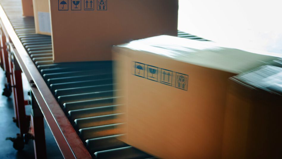 Una cinta transportadora con cajas de cartón sobre ella