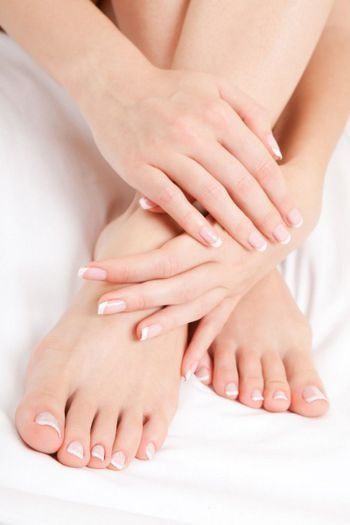 Un primer plano de las manos y los pies de una mujer en una cama.