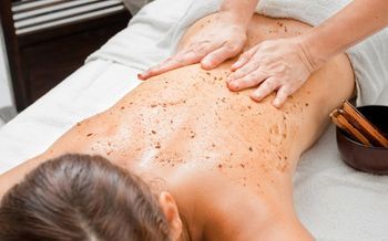 Una mujer está recibiendo un masaje exfoliante corporal en un spa.