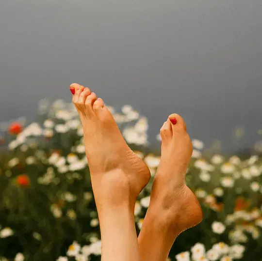 Un primer plano de los pies de una mujer en un campo de flores.