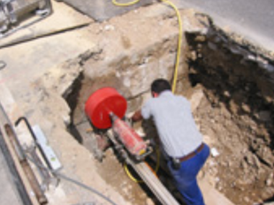 Obrero manejando una máquina de corte roja en una gran excavación.