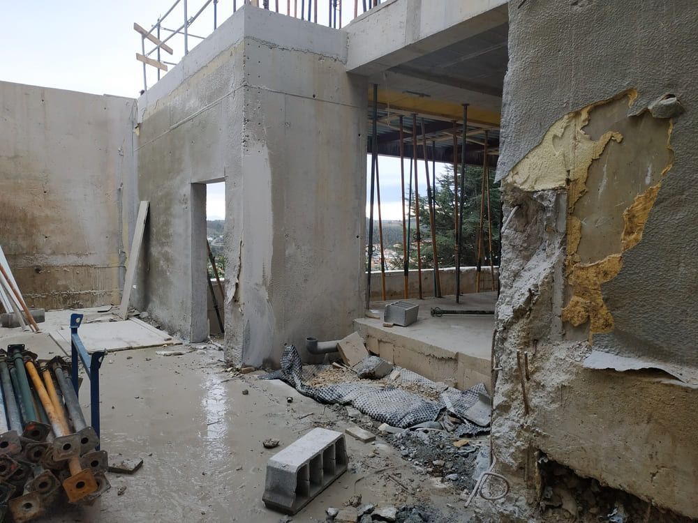 Interior de un edificio de hormigón parcialmente demolido con escombros, andamios y paredes dañadas.