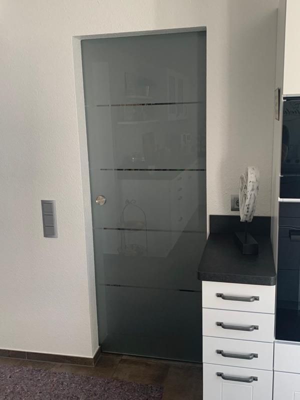 Eine Küche mit Glasschiebetür und weißen Schränken.