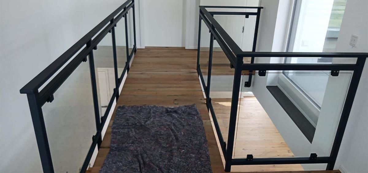 Ein Flur mit Glasgeländer und Treppe in einem Haus.