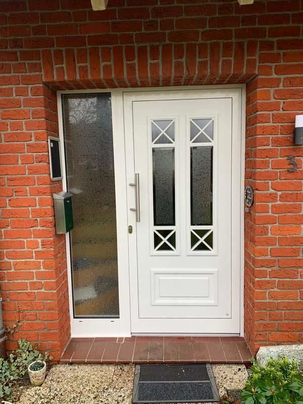 An einem roten Backsteingebäude befindet sich eine weiße Tür.