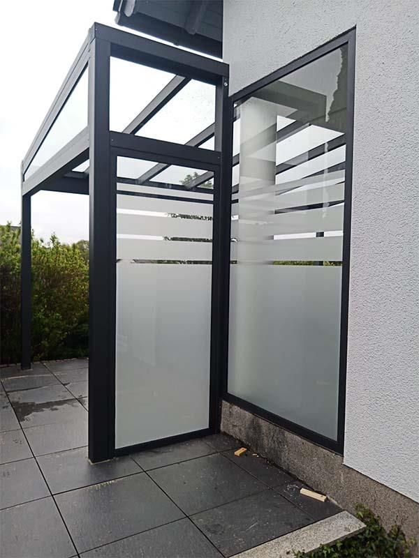 Ein weißes Gebäude mit einem Glaszaun und einer Glastür.