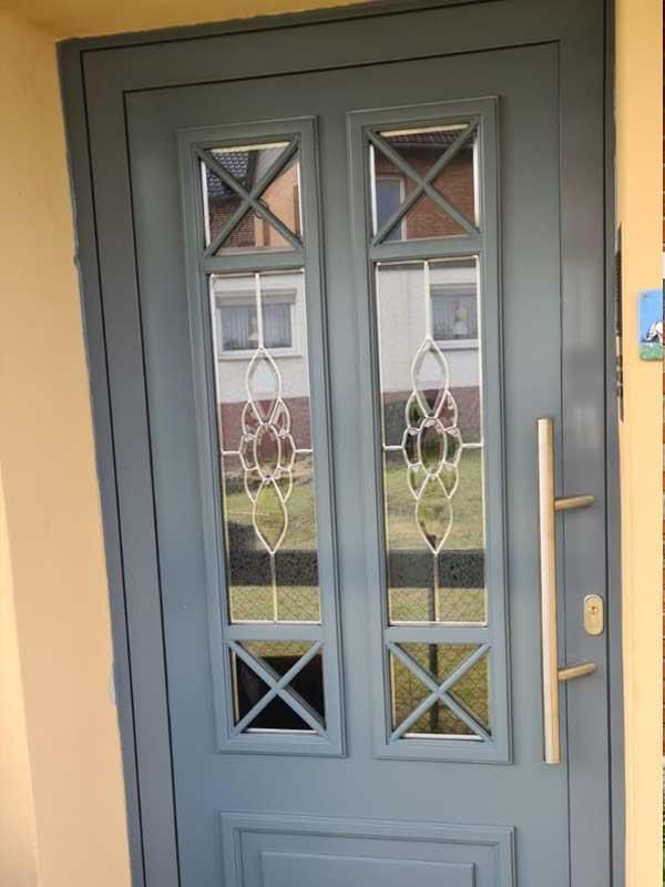 Eine blaue Haustür mit Buntglasfenstern und einem Edelstahlgriff.