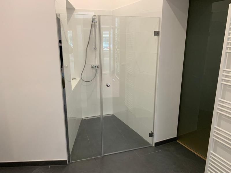 Ein Badezimmer mit ebenerdiger Dusche mit Glastür.