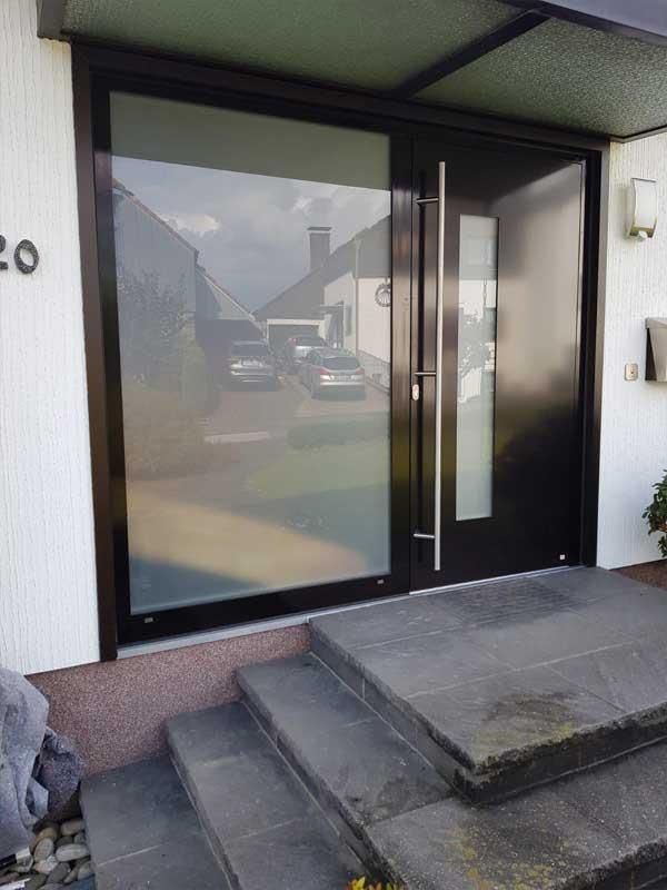 Die Eingangstür eines Hauses mit Treppe und großem Fenster.