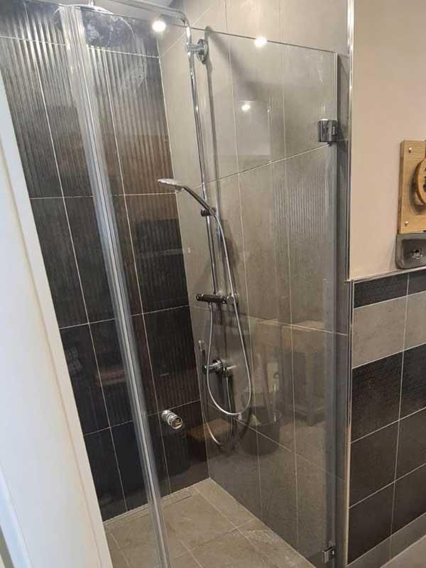 Ein Badezimmer mit ebenerdiger Dusche mit Glastür.