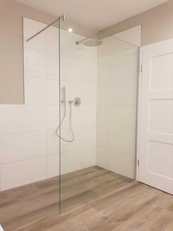 Ein Badezimmer mit ebenerdiger Dusche und Spiegel.