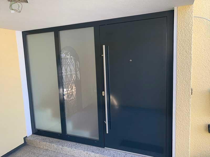 In einem Gebäude befindet sich eine schwarze Tür mit einem Edelstahlgriff.