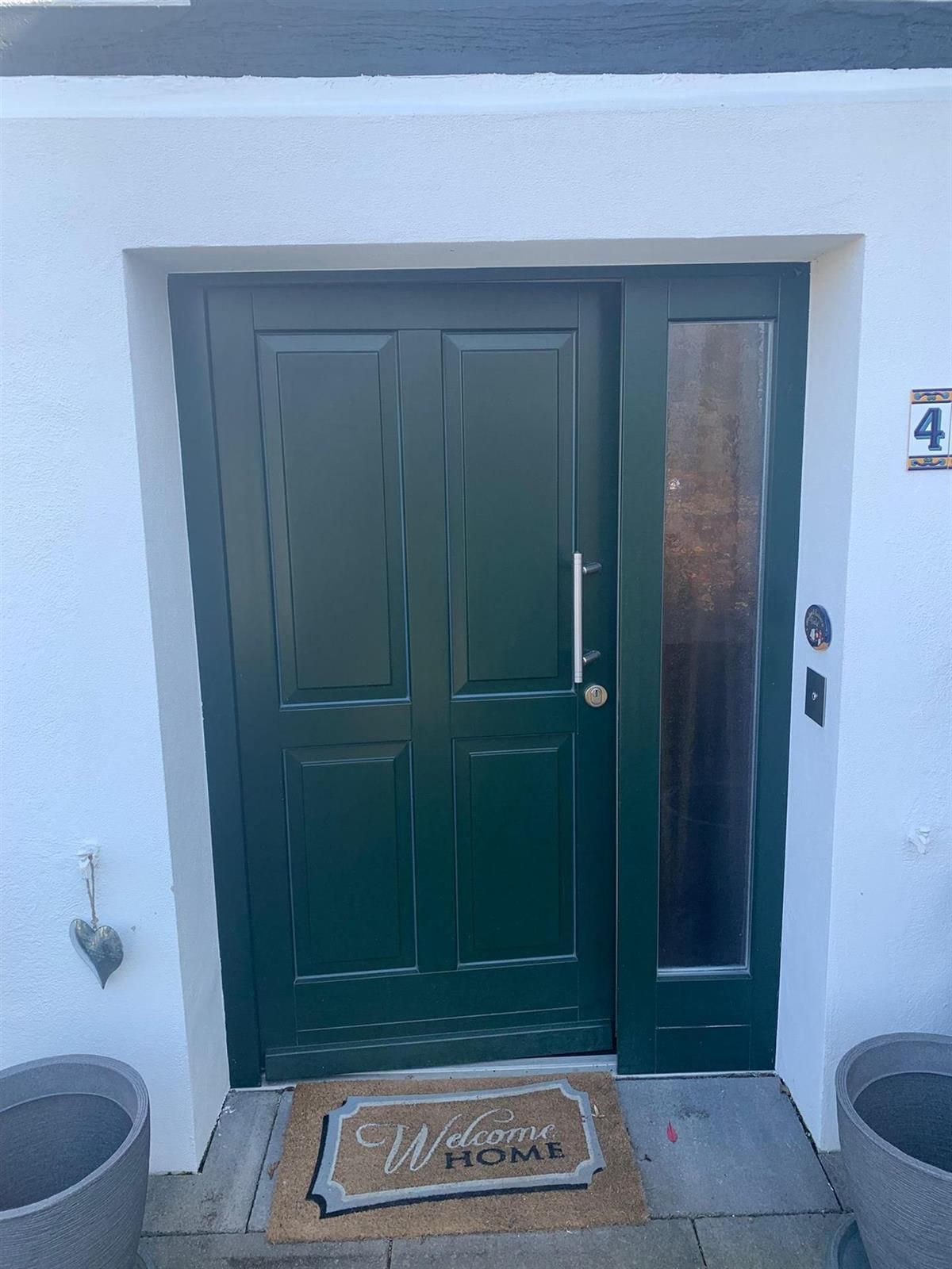 Eine grüne Tür mit einer Fußmatte davor