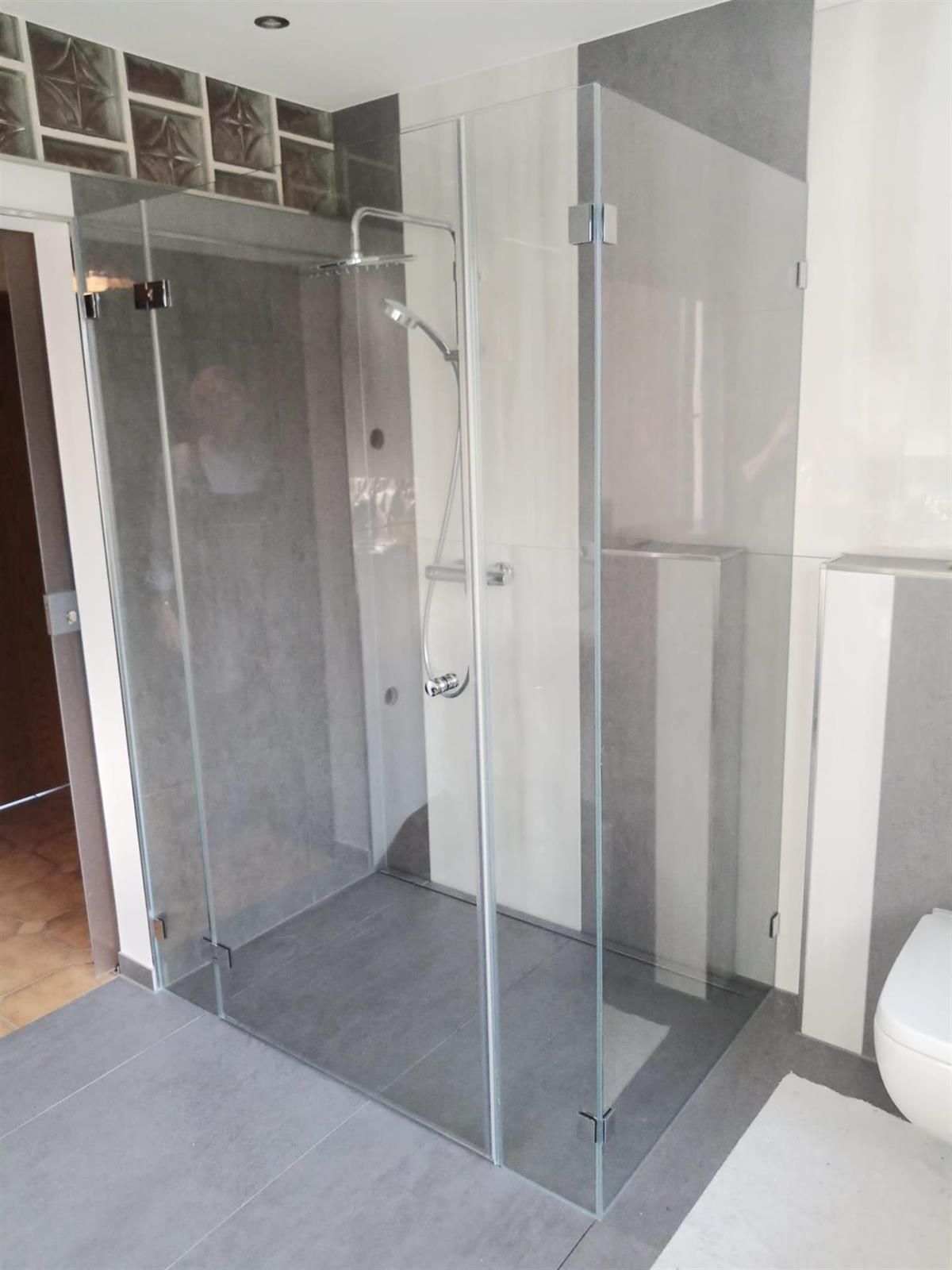 Ein Badezimmer mit ebenerdiger Dusche und Toilette.