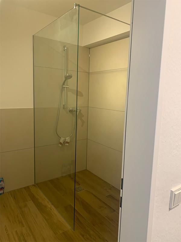 Ein Badezimmer mit ebenerdiger Dusche und Holzboden.