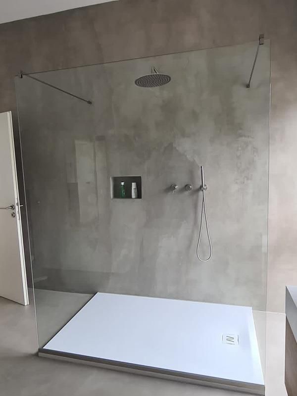 Eine ebenerdige Dusche mit weißer Duschwanne und Duschkopf.