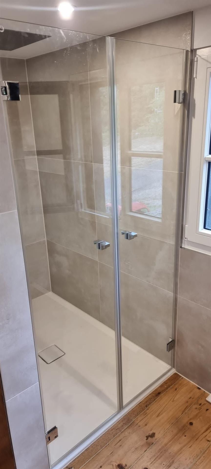 Ein Badezimmer mit ebenerdiger Dusche und Fenster.