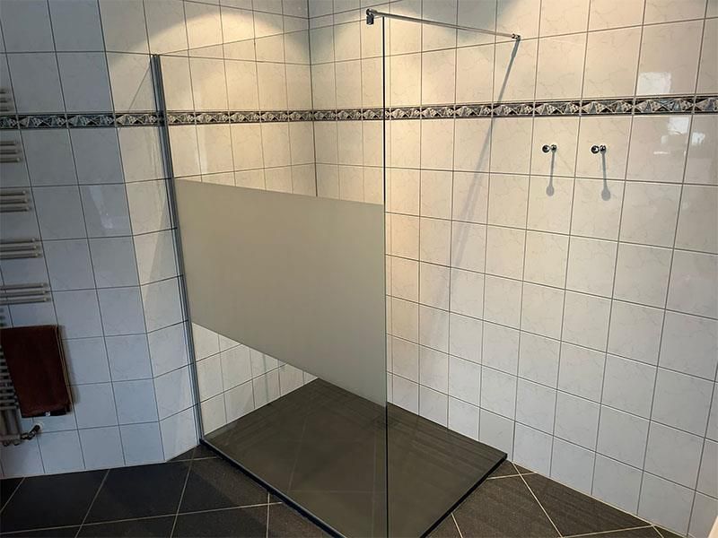 Ein Badezimmer mit weißen Fliesen und einer ebenerdigen Dusche